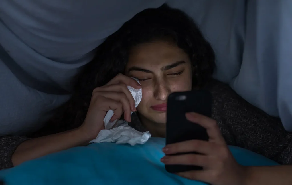 girl student under covers at night feeling isolated and crying