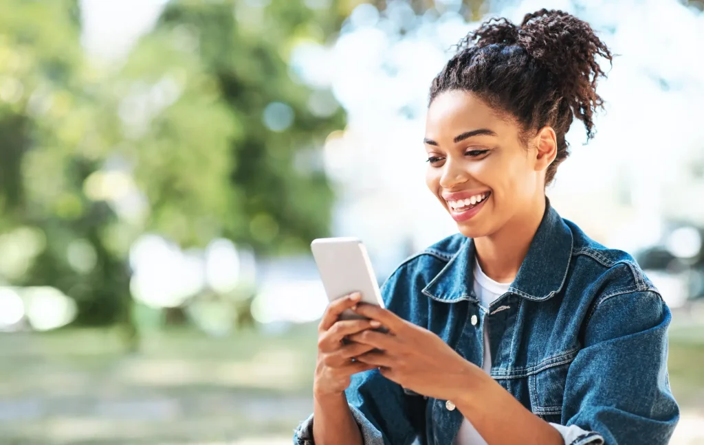 student outside in nature checking wellbeing app on her phone