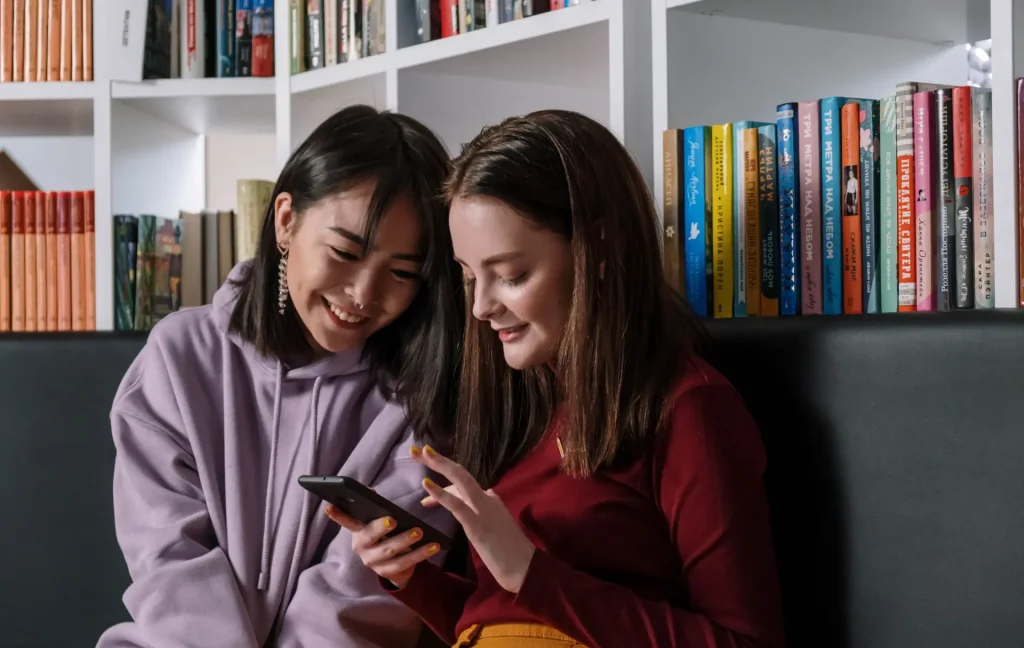 2 female teenage girls looking at phone screen following tiktok video on wellbeing
