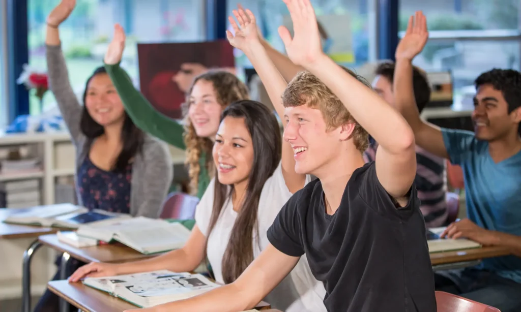 students raising hands and being engaged in class