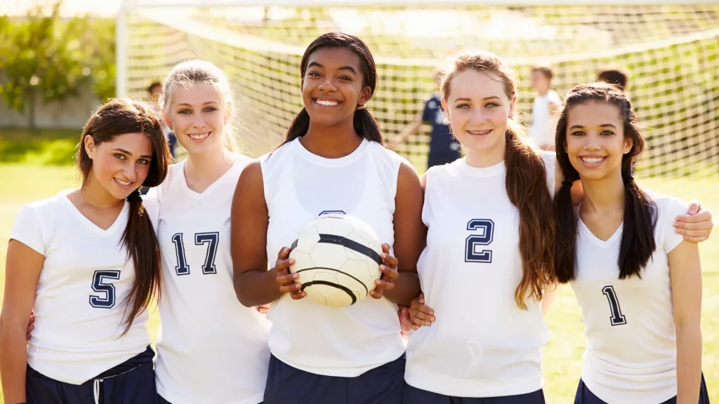 team of high school female handball players of different races, all smiling and hugging
